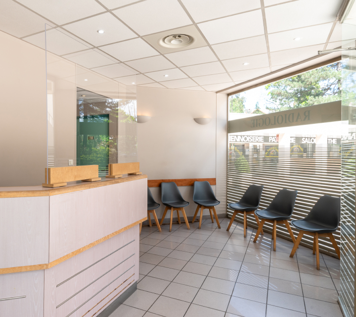 Salle d'attente moderne avec un comptoir de réception et des chaises alignées contre le mur | Centre versaille | Imagerie Cardinet | Région Parisienne