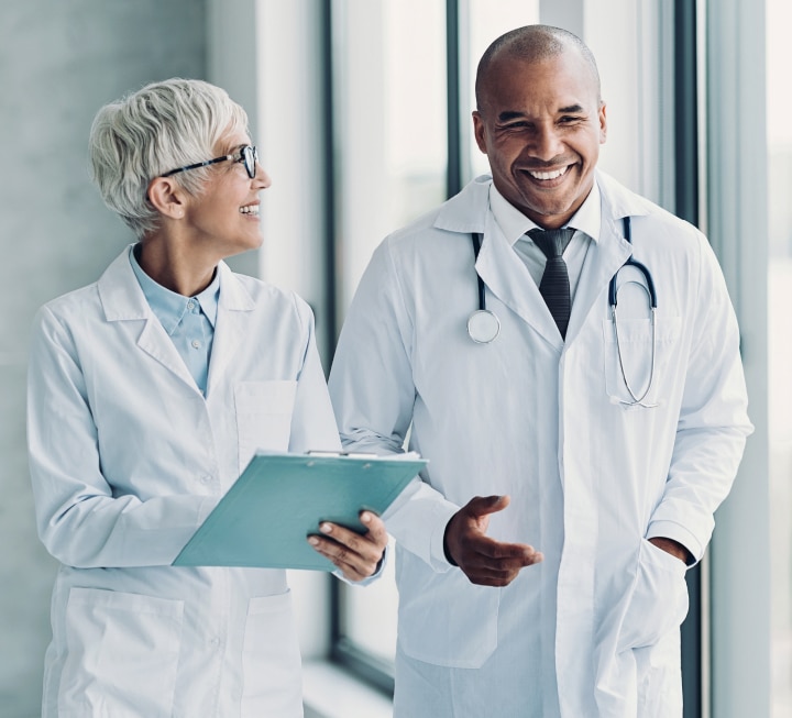 Deux médecins souriants discutant dans un couloir lumineux | Devenir médecin | Imagerie Cardinet | Région Parisienne