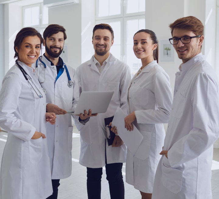 Groupe de cinq médecins discutant autour d'un ordinateur portable - notre équipe | Imagerie Cardinet | Région Parisienne