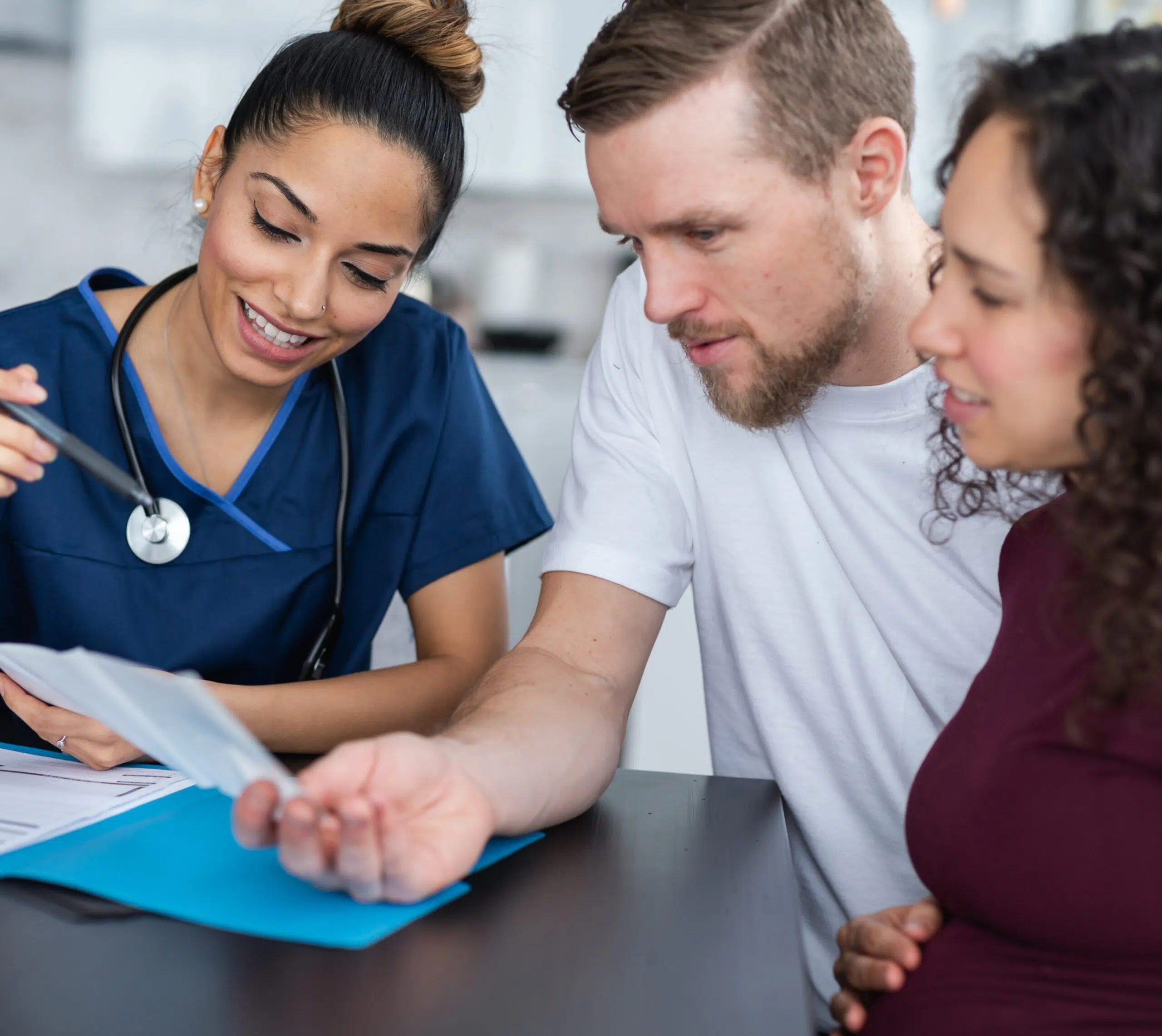 Médecin expliquant des documents à un couple dont la femme est enceinte | Bilant fertilité | Imagerie Cardinet | Région Parisienne