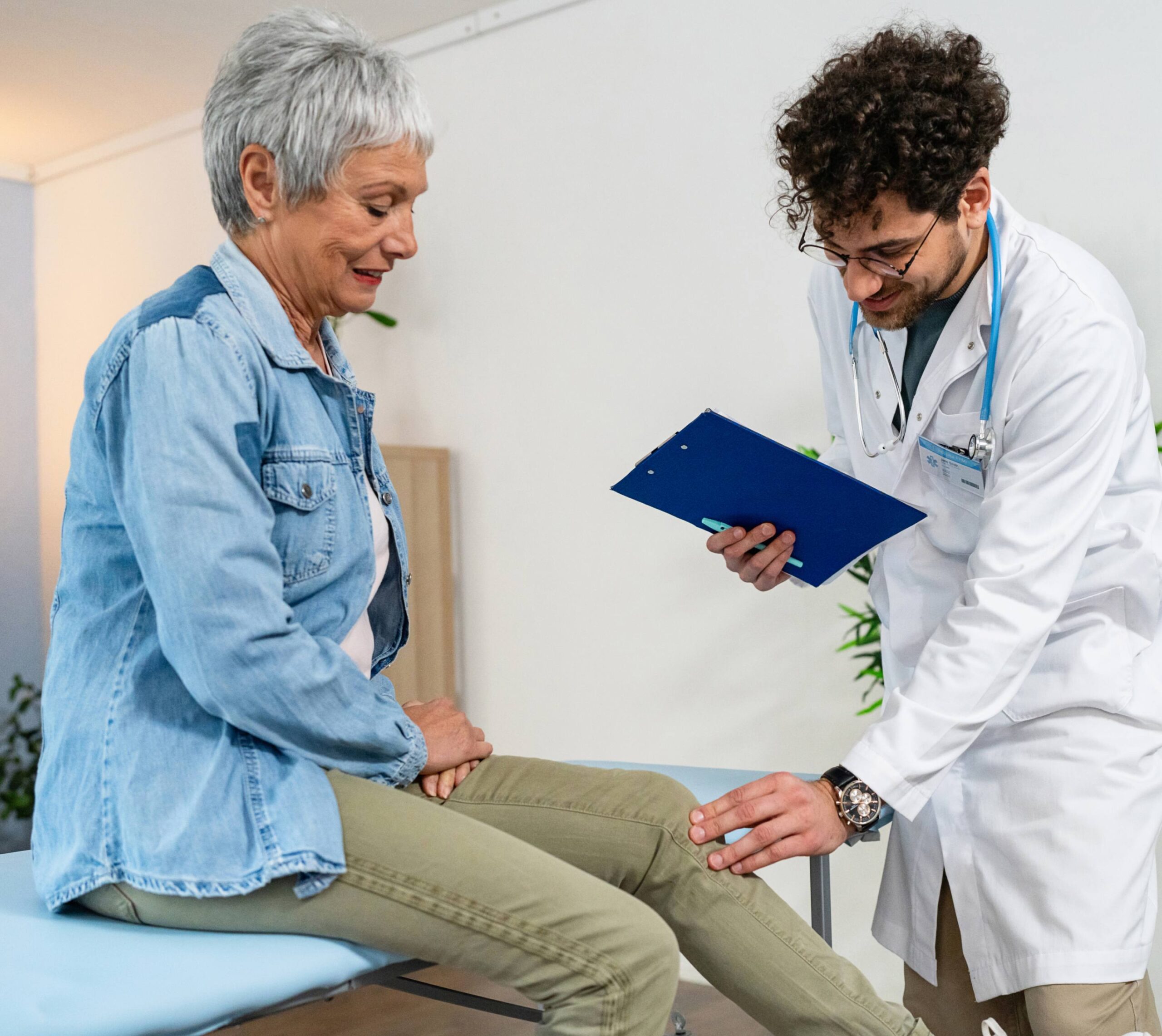 Médecin examine le genou d'un patient assis sur une table d'examen | Infiltration | Imagerie Cardinet | Région Parisienne