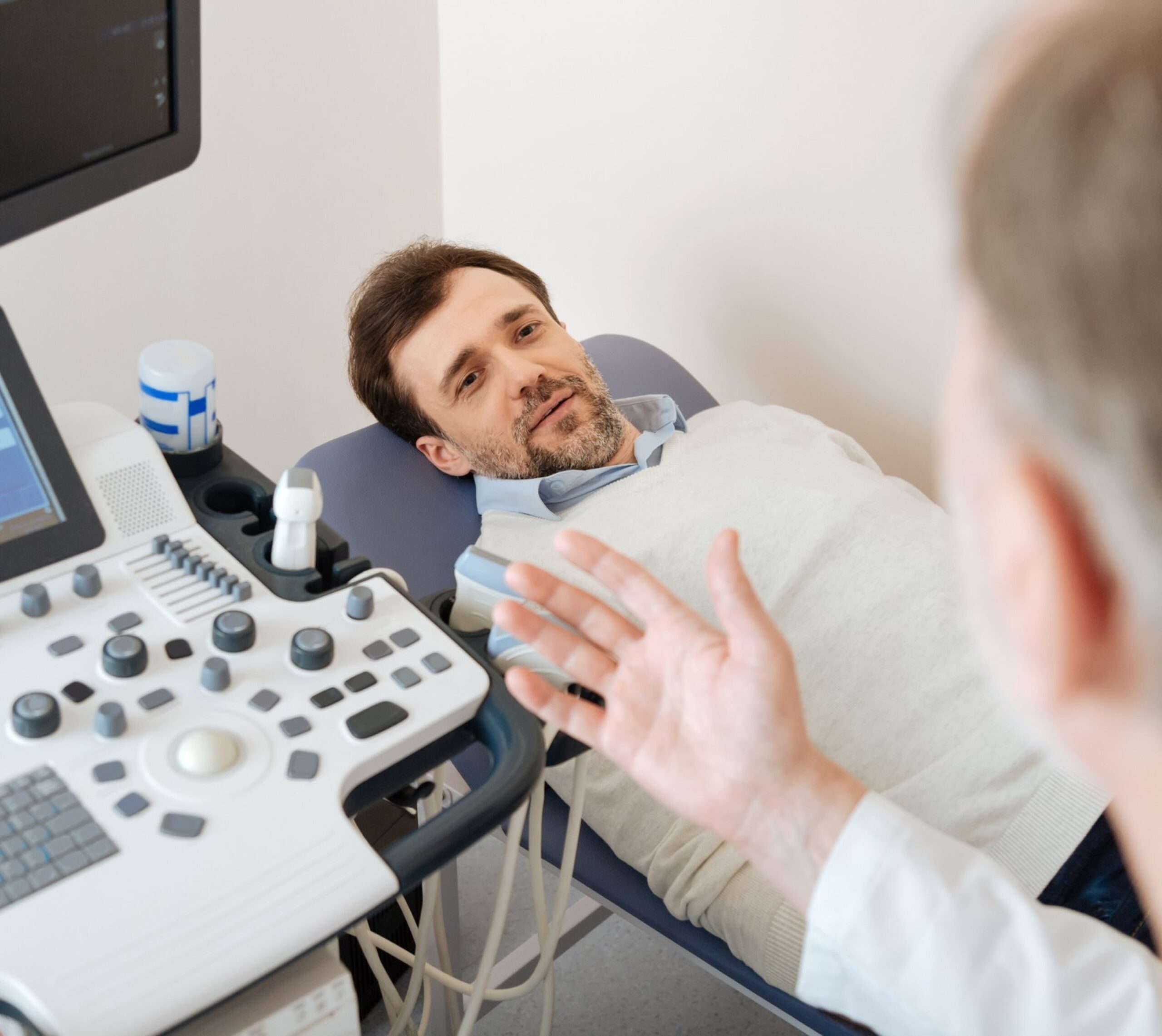 Homme allongé sur une table d'examen médical avec un appareil d'échographie à côté - échographie testiculaire | Imagerie Cardinet | Région Parisienne