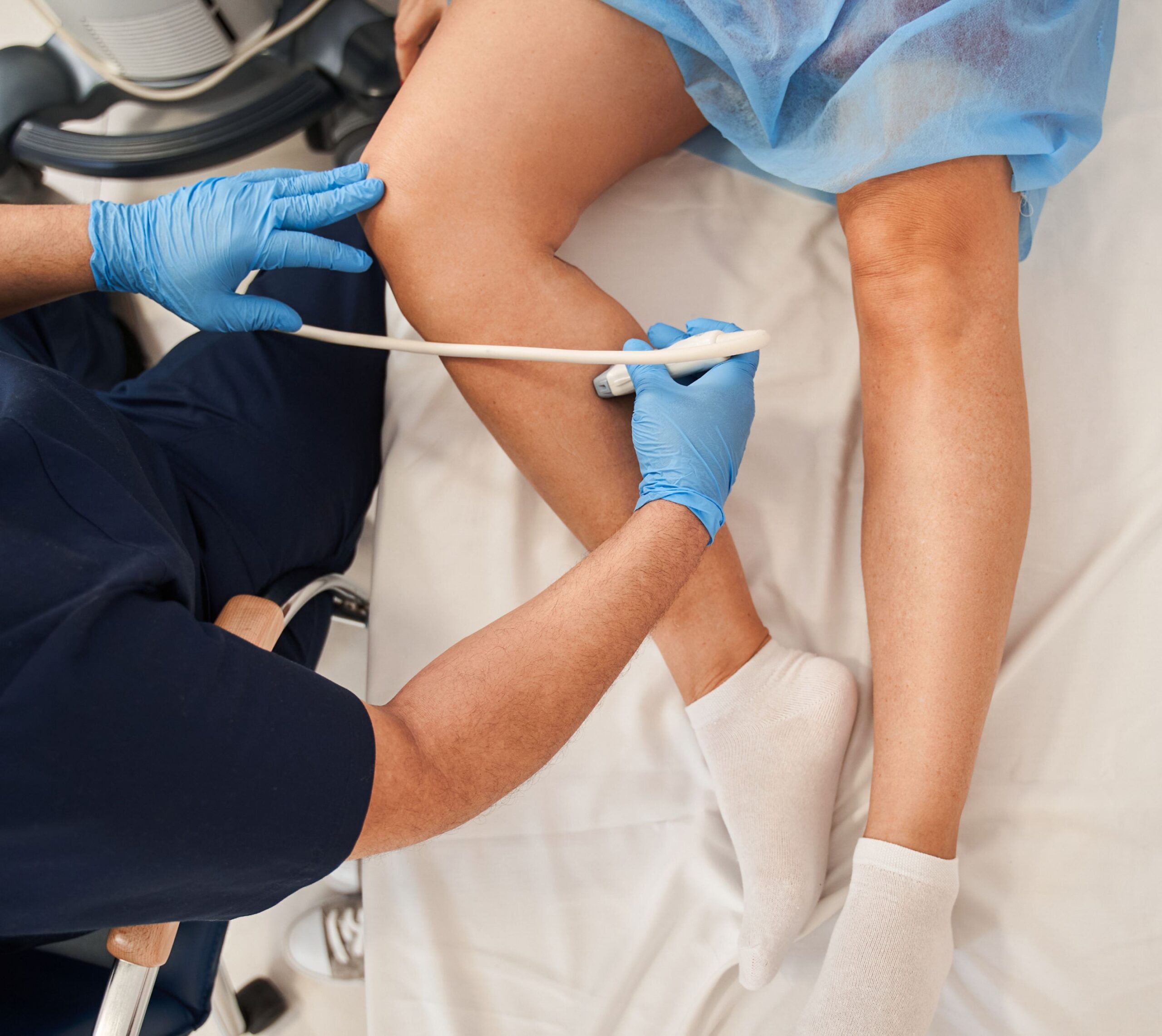 Médecin faisant une échographie sur la jambe d'un patient allongé | échographie vasculaire | Imagerie Cardinet | Région Parisienne