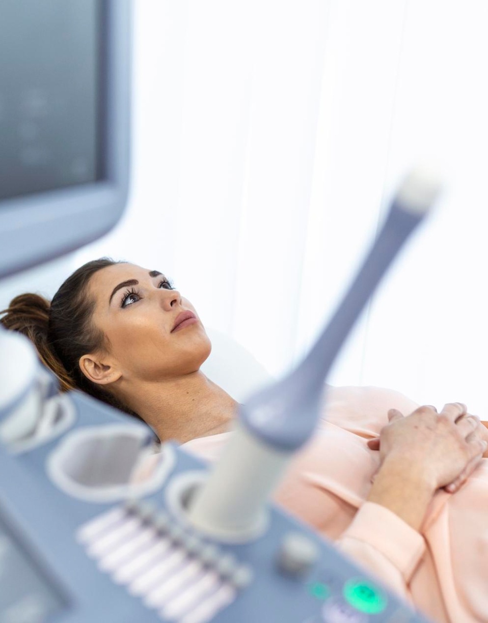 Femme allongée mains croisées subit une échographie médicale - échographie pelvienne | Imagerie Cardinet | Région Parisienne