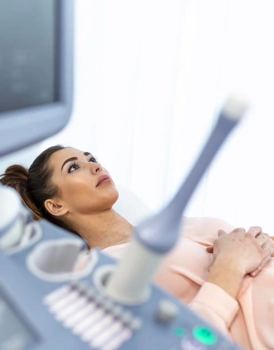 Femme allongée mains croisées subit une échographie médicale - échographie pelvienne | Imagerie Cardinet | Région Parisienne