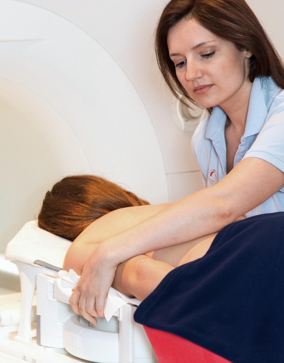 Femme allongée sur le ventre assistée pour un examen médical - IRM mammaire | Imagerie Cardinet | Région Parisienne